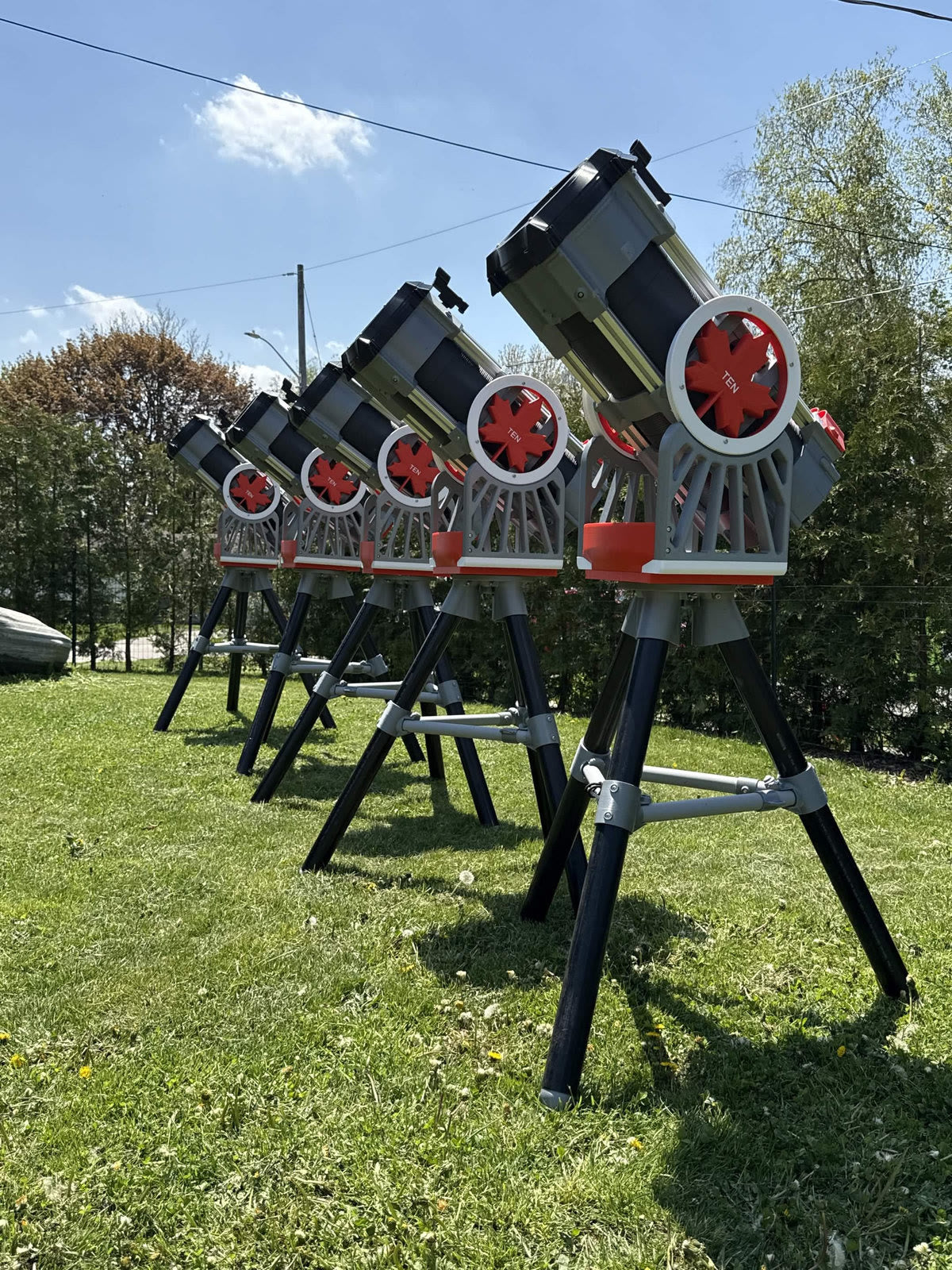 A row of red and white 3D-printed Skyward 200 telescopes on tripods